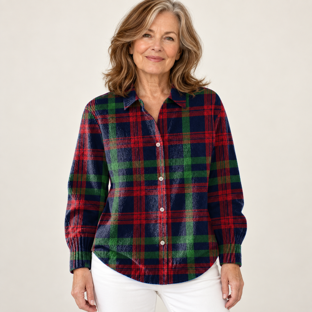 Mature British woman wearing the GUNELLE blouse on a clean warm off-white studio background