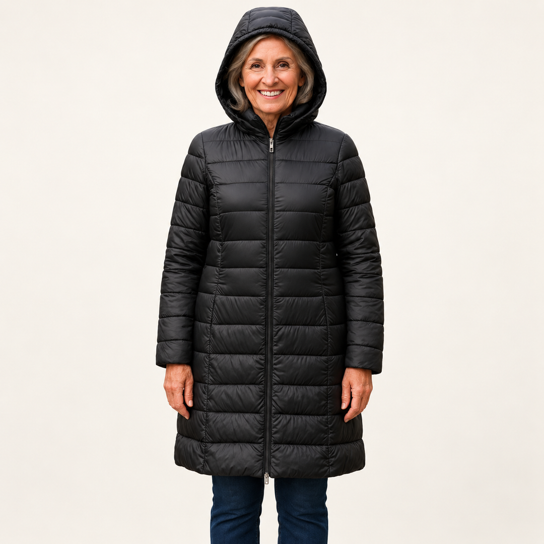 Mature British woman wearing the HELSA Black padded jacket on a clean warm off-white studio background