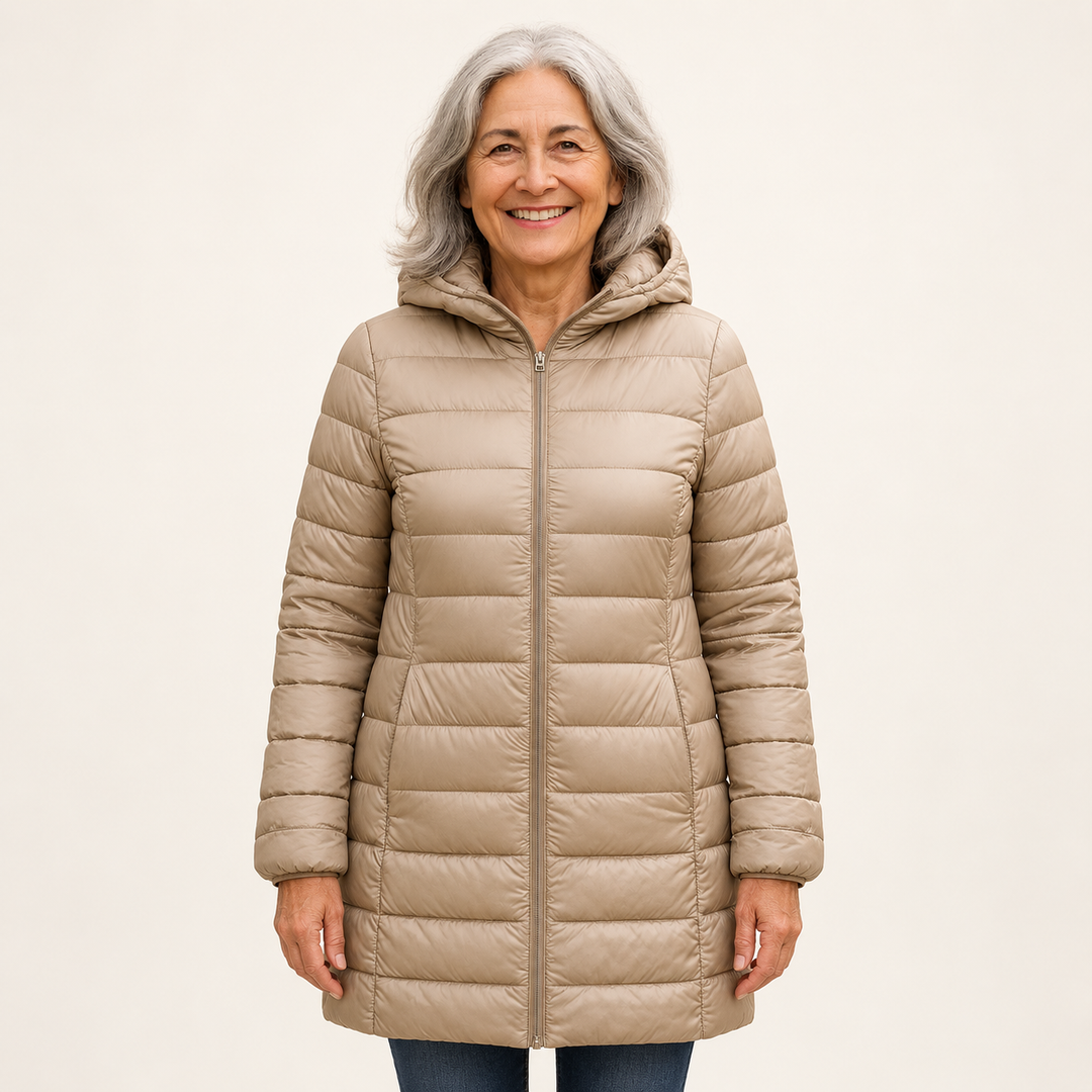 Mature British woman wearing the HELSA Champagne padded jacket on a clean warm off-white studio background