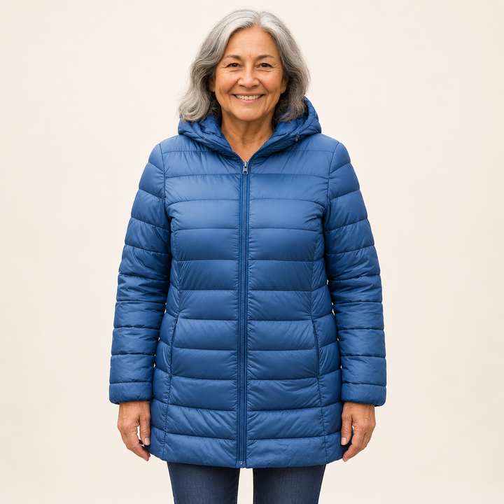 Mature British woman wearing the HELSA Indigo padded jacket on a clean warm off-white studio background