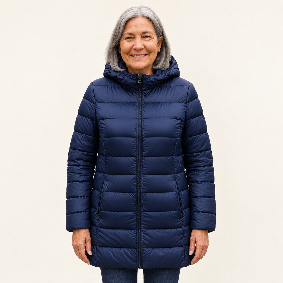 Mature British woman wearing the HELSA Navy Blue padded jacket on a clean warm off-white studio background