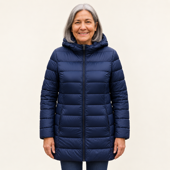 Mature British woman wearing the HELSA Navy Blue padded jacket on a clean warm off-white studio background