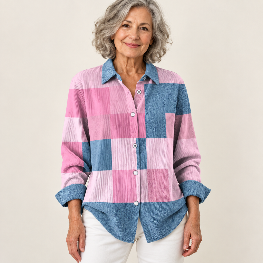 Mature British woman wearing the NORAYA blouse on a clean warm off-white studio background
